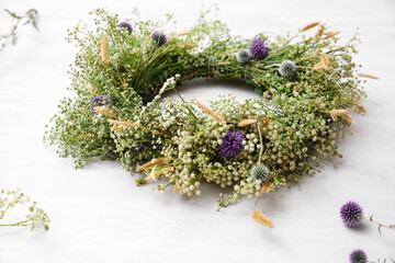 Beautiful wreath made of wildflowers on white table © New Africa