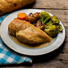 Chicken in mustard sauce with roasted vegetables in wooden background