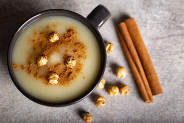 Boza or Bosa, traditional Turkish drink with roasted chickpea in ceramic bowl with cinnamon on stone background. Top view.