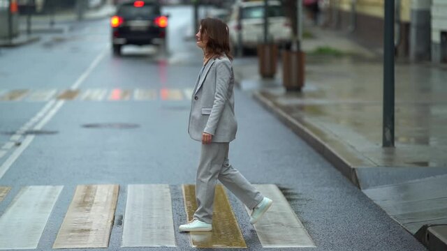 female pedestrian is walking on crosswalk in city street, lady is wearing cervical collar