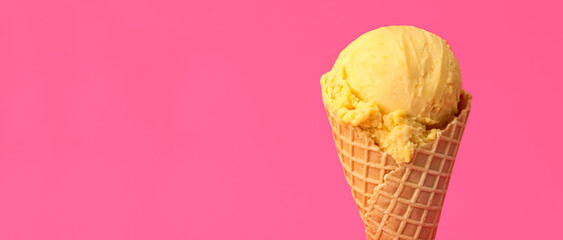 Delicious yellow ice cream in waffle cone on pink background. Space for text