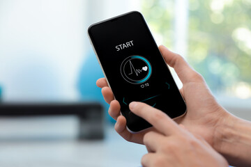 Young woman using fitness app on smartphone indoors, closeup