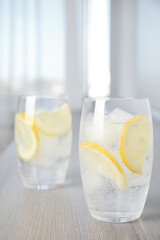Soda water with lemon slices and ice cubes on wooden table indoors