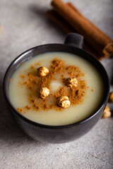 Boza or Bosa, traditional Turkish drink with roasted chickpea in ceramic bowl with cinnamon on stone background. 