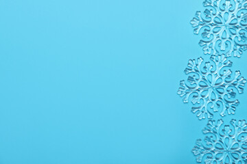 Beautiful decorative snowflakes on light blue background, flat lay. Space for text
