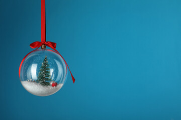 Beautiful Christmas snow globe hanging on blue background, space for text