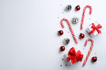 Flat lay composition with candy canes and Christmas decor on white background. Space for text