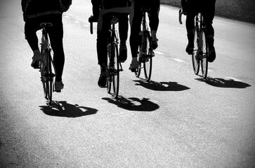 four backlit cyclists pedaling together