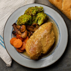 Chicken in mustard sauce with roasted vegetables in dark background