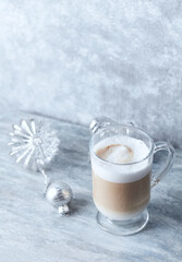 Coffee with milk and Christmas ornaments on rustic wooden background.
