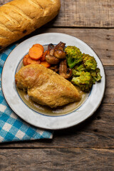 Chicken in mustard sauce with roasted vegetables in wooden background