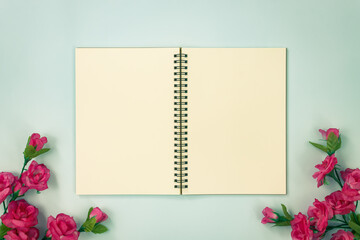 Top Table Spiral Notebook or Spring Notebook Mock up in Unlined Type on Center Frame and Rose Flowers at Bottom on Blue Pastel Minimalist Background in Vintage Tone