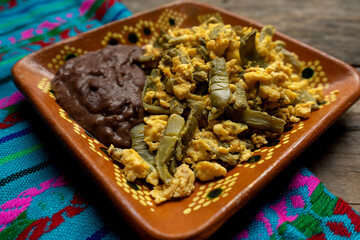 Mexican scrambled eggs with nopal cactus and beans on wooden background