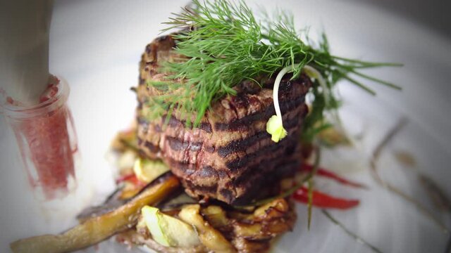 Grilled Fillet Beef Steak with sauce, tomatoes and rosemary on a white plate