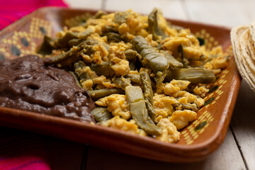 Mexican scrambled eggs with nopal cactus and beans on white background
