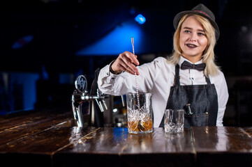 Girl barman creates a cocktail in the alehouse
