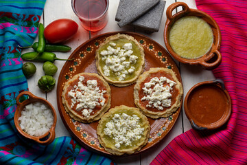 Mexican picaditas with sauce and fresh cheese on white background