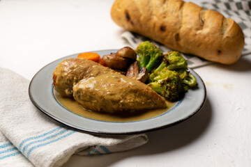Chicken in mustard sauce with roasted vegetables in white background