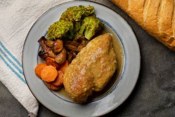 Chicken in mustard sauce with roasted vegetables in dark background