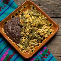 Mexican scrambled eggs with nopal cactus and beans on wooden background