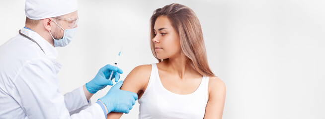 Doctor gives a syringe with vaccine to patient at clinic.