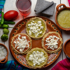 Mexican picaditas with sauce and fresh cheese on white background