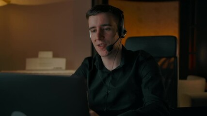 Call center at home. Caucasian man helps to customer and look at camera. European male helping to company clients from his home at the evening.