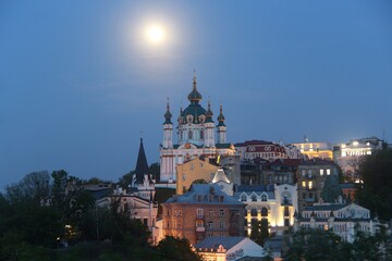 Fototapeta na wymiar St. Andrew's Church was built in the Baroque style in 1749-1754 by the architect Rastrelli. It is located on Andreevskaya Hill above the historical part of Podol. Full Moon. Kiev city.