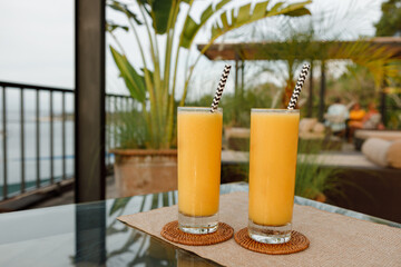 Fresh mango smoothie  juice in two glasses on  the  table outdoors. Summer refreshing drink