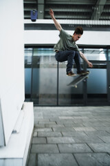 Fototapeta na wymiar Young Caucasian man jumping on a skateboard on the street.