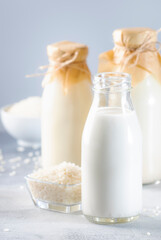 Obraz na płótnie Canvas Rice milk in bottles, closeup, gray background. Non dairy alternative milk. Healthy vegetarian food and drink