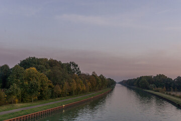 Fototapeta na wymiar Straight water channel in germany munsterland at sunset in autumn