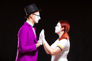 Portrait of two mime artist, isolated on black background. Young man and woman stand opposite...