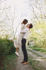 Man and woman in blooming garden on spring day. Couple in love spend time in spring garden. Flowers on background.