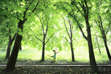 Fototapeta na wymiar Young Caucasian woman dancing ballet in the spring forest.
