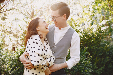 Man and woman in blooming garden on spring day. Couple in love spend time in spring garden. Flowers on background.