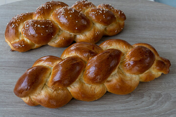 Two braided Brioche breads on wooden board