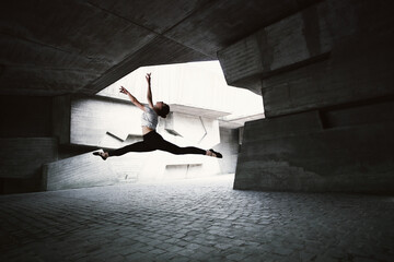 Young caucasian ballerina dancing ballet on the street in summer.