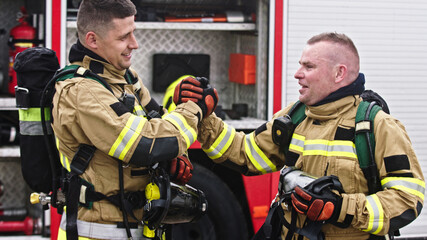 Two firefighters shaking hands after successful fire drill. High quality photo