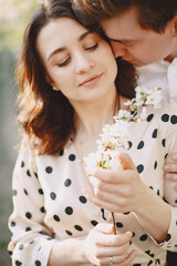 Man and woman in blooming garden on spring day. Couple in love spend time in spring garden. Flowers on background.