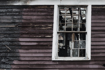 After a house fire: charred wood siding and broken window