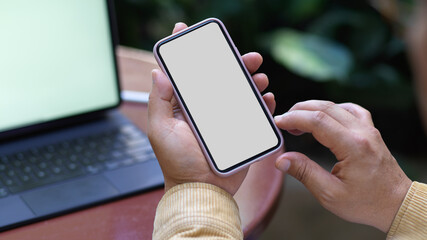 Male hand using smartphone while working with tablet in garden