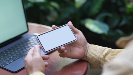 Male hand using horizontal smartphone while working with tablet in garden