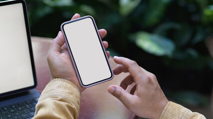 Male hand using smartphone while working with tablet in garden