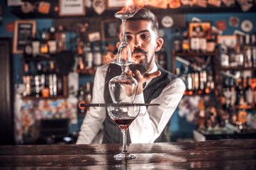 Professional bartending decorates colorful concoction while standing near the bar counter in pub