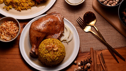 Tasty chicken biryani with rice marinated in spices serving with fried onion on dinning table