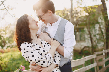 Man and woman in blooming garden on spring day. Couple in love spend time in spring garden. Flowers on background.