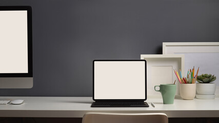 Worktable with computer, laptop, and decorations in home office