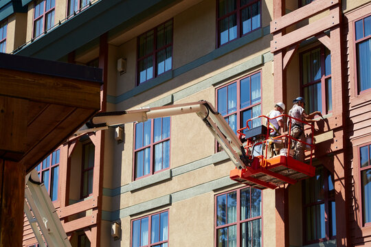 Construction workers suspended on platform finishing the masontry and exterior of a building