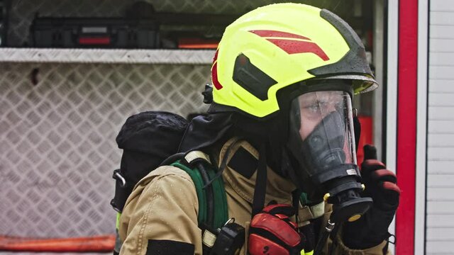 Close up, portrait of firefighter wearing gas mask in front of the fire engine. High quality 4k footage